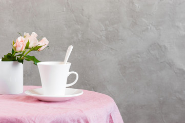 The white cup of tea or coffee with milk on the table coated with pink tablecloth