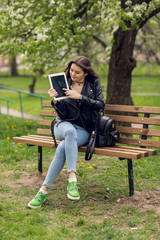 Portrait of young girl holding digital tablet in the park