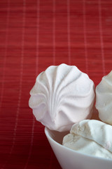 White and pink zephyr on porcelain plate on red wooden background