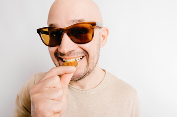 Closeup funny bald man portrait. Greedy cryptocurrency miner biting bitcoin metal coins to check...