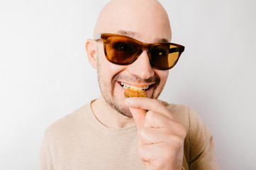 Closeup funny bald man portrait. Greedy cryptocurrency miner biting bitcoin metal coins to check...