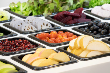 Salad bar with various fresh vegetables and other foods.