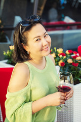Beautiful Asian woman with a glass of wine in a summer cafe