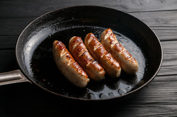 Black pan with delicious sausages on the grill on the kitchen table.