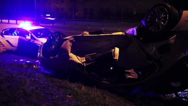 Night incident on the road. Car turned over on the road in the light of police flashers