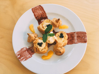 profiteroles with cream and orange slices and mint leaves