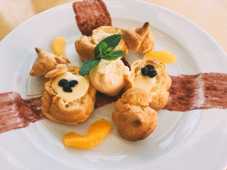 profiteroles with cream and orange slices closeup