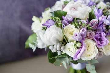 Brides wedding bouquet with peonies, freesia and other flowers on black arm chair. Light and lilac spring color. Morning in room