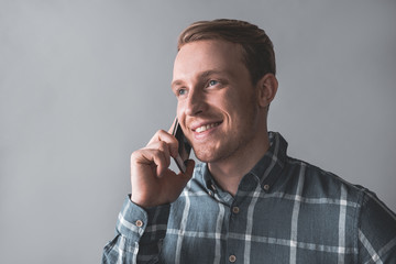 Portrait of young guy talking by cellphone and looking aside. Isolated on background