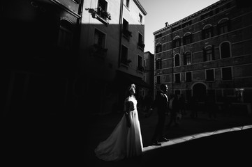 Handsome groom kissing happy bride in street