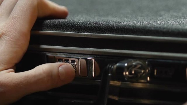 Male hands entering secret code and opening black briefcase, money protection
