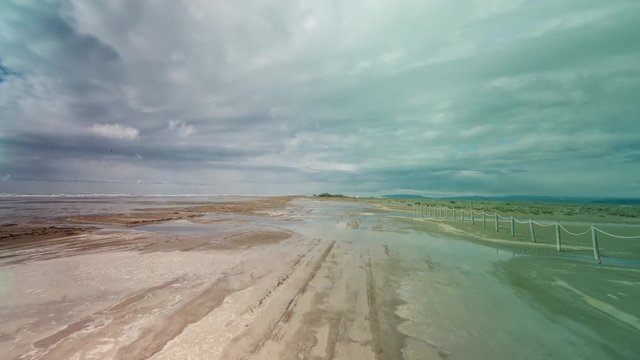 hyperlapse pov shot with a camera attached to the front of an off road vehicle driving over a flooded beach in the delta d'ebro park, spain