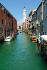 Channel with turquoise water, San Giorgio dei Greci belfry, Venice, Italy