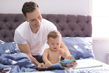 Obraz premium Young father reading book with his cute little son on bed