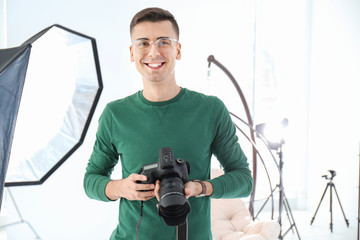 Young photographer with professional camera in studio