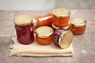 Jars with different sweet jam on table