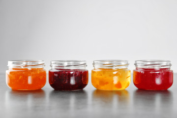 Jars with different sweet jam on grey background