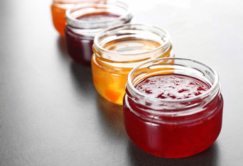 Jars with different sweet jam on table