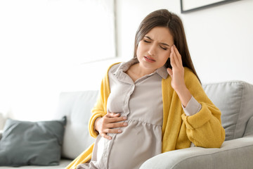 Young pregnant woman suffering from headache at home