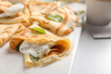 Thin pancakes with sour cream on board