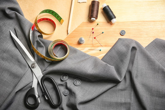 Composition with fabric and accessories for tailoring on wooden background