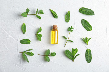 Bottle with mint essential oil and fresh herbs on white background, flat lay