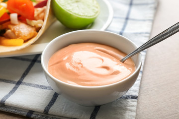 Tasty creamy sauce for fish taco in bowl on wooden table