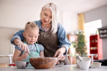 Obraz na płótnie Canvas Little girl and her grandmother preparing dough together in kitchen