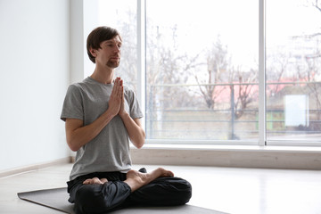 Young man practicing yoga indoors