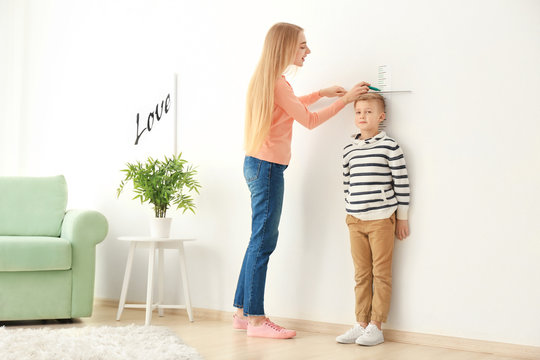 Young woman measuring height of little boy at home