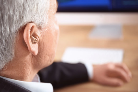 Mature man with hearing aid indoors