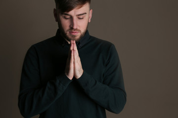 Fototapeta na wymiar Religious young man praying on dark background