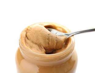 Jar and spoon with creamy peanut butter on white background