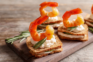 Delicious small sandwiches with shrimps on wooden board