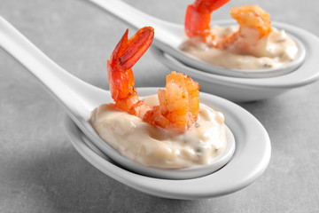 Delicious snacks with shrimp in spoons on grey background