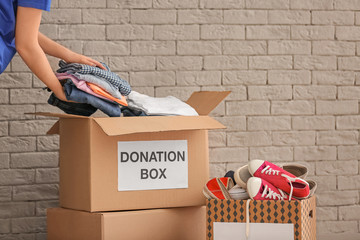 Volunteer collecting clothes into donation boxes indoors