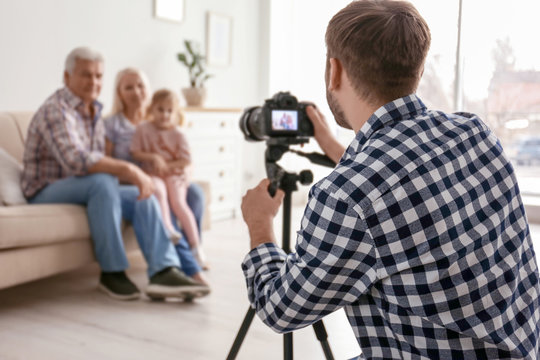 Professional photographer taking photo of family on sofa in studio
