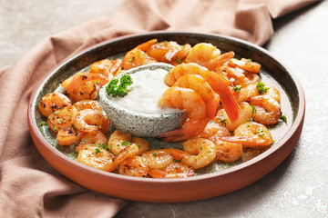 Plate with fried shrimps and sauce on grey background