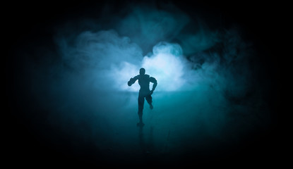 Silhouette of man standing on an dark foggy toned background. Decorated photo with man figure on table with light.