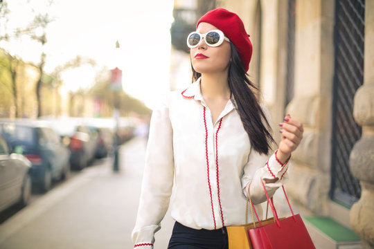 Stylish woman walking in the street, holding shopping bags