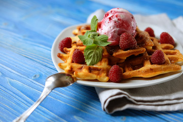 Plate of belgian waffles with ice cream and fresh berries over blue wooden background, top view