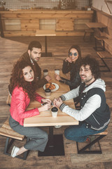 Top view of joyful couples having double date in restaurant. They are looking at camera and laughing