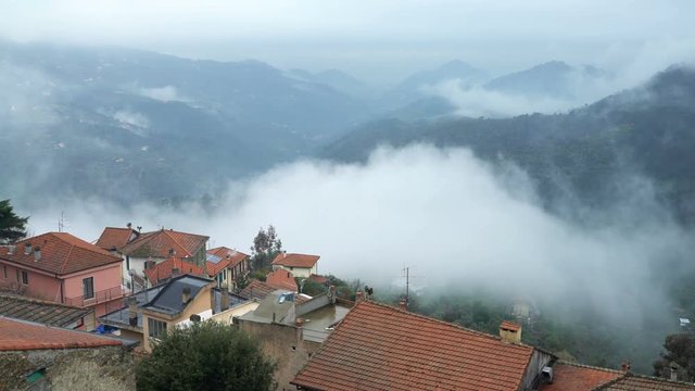 Early foggy morning in the Alpine town. Fog from the mountains makes its way along the medieval streets. Perinaldo, Liguria, Italy.