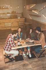 Top view of joyful students having fun in cafe. They are chatting and smiling while drinking hot beverage