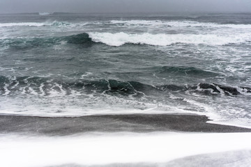 Blizzard on a beach of the Pacific ocean with black sand