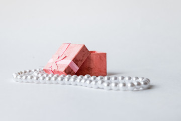 pink box for jewelry with bow and white necklace on white background