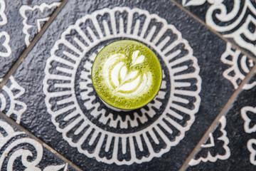 Cup of hot matcha cappucino is on art background floor