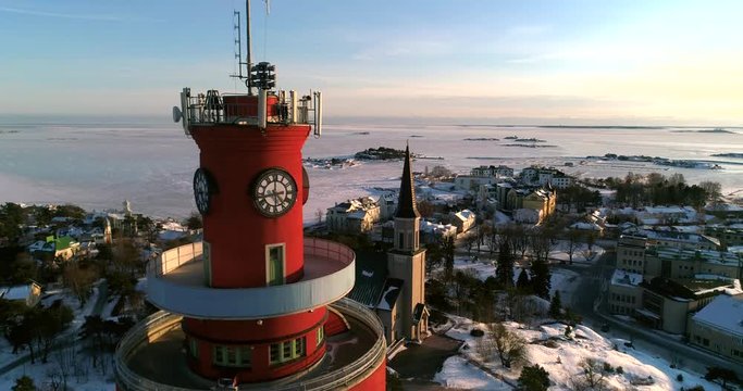 Church in a city, Cinema 4k aerial view around a water tower and revealing a church, a icy Hanko cityscape, on a cold sunny winter evening dawn, in Uusimaa, Finland