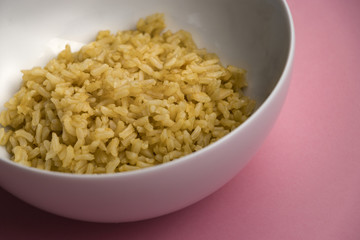 Organic Cooked Brown Rice in a White Bowl on a Pink Background