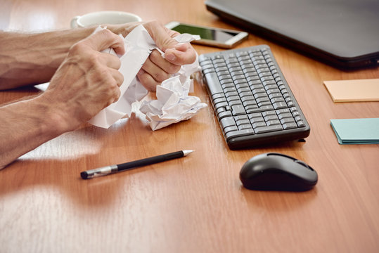 Tired worker making mistake in document and crumpling paper